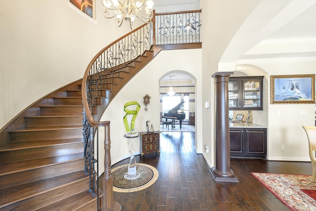 stairs with hardwood / wood-style flooring, a high ceiling, arched walkways, and ornate columns