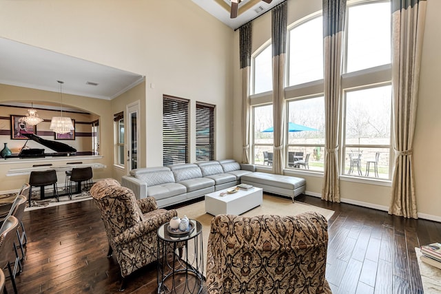 living area with an inviting chandelier, wood-type flooring, baseboards, and crown molding