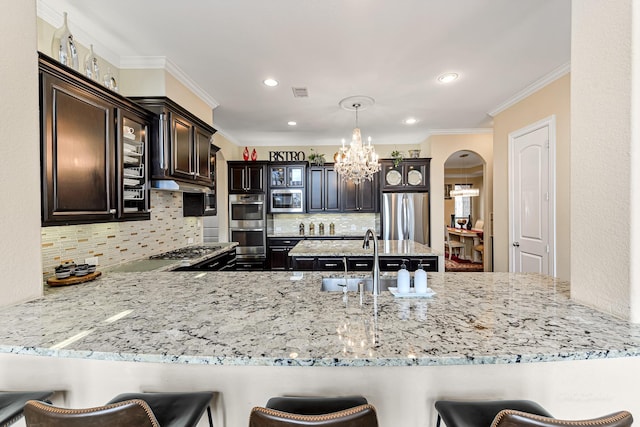 kitchen featuring dark brown cabinetry, arched walkways, a peninsula, stainless steel appliances, and crown molding