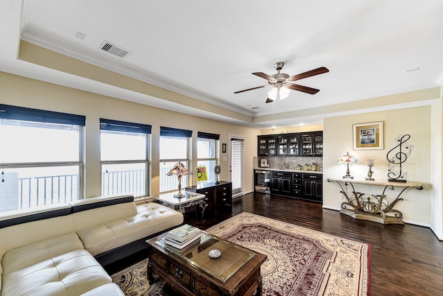 living area with a raised ceiling, visible vents, dark wood finished floors, and bar area