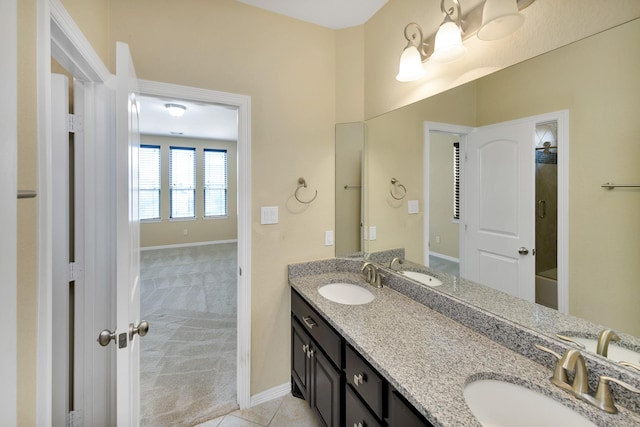 bathroom with a sink, baseboards, and double vanity