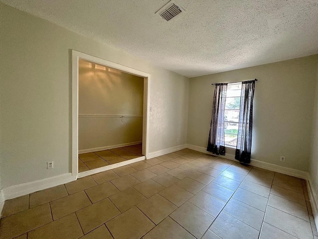 spare room with tile patterned flooring and a textured ceiling