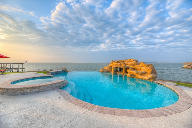 view of swimming pool featuring an in ground hot tub and a water view