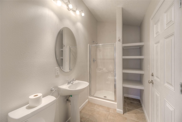 bathroom with sink, a shower with door, toilet, and tile patterned floors