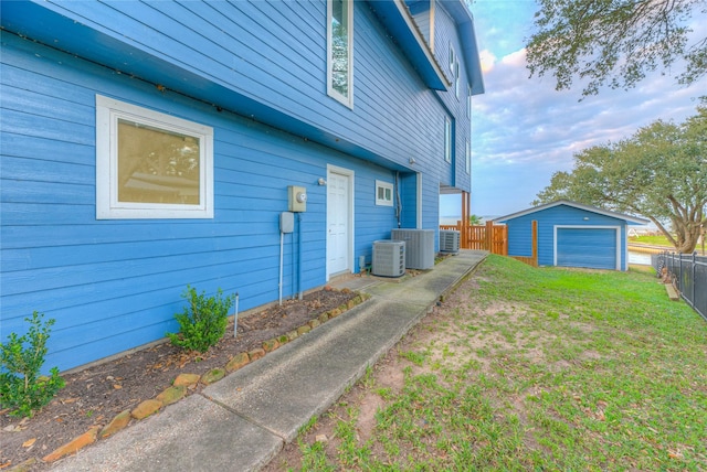 view of property exterior with a garage, an outbuilding, a lawn, and cooling unit