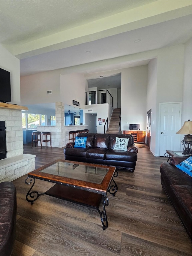 living room featuring hardwood / wood-style flooring, a towering ceiling, and a fireplace