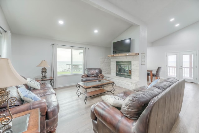 living room with light hardwood / wood-style floors, vaulted ceiling, and french doors