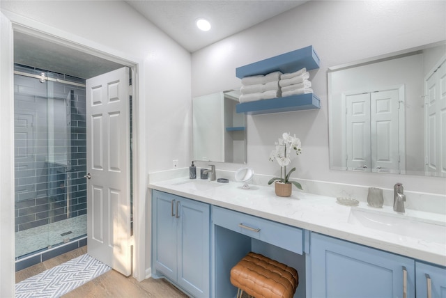 bathroom with hardwood / wood-style flooring, a tile shower, and vanity