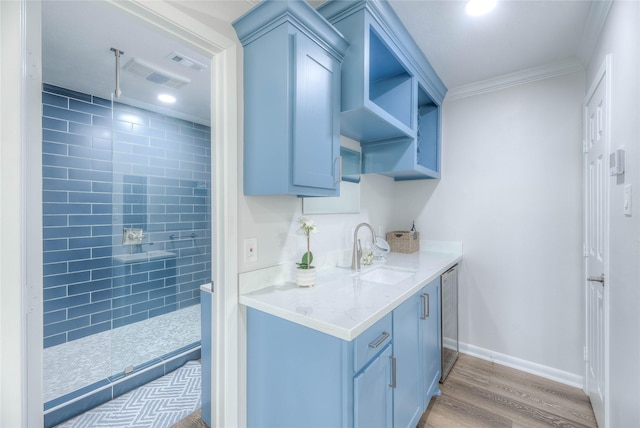 kitchen featuring dishwasher, light stone countertops, hardwood / wood-style floors, ornamental molding, and sink