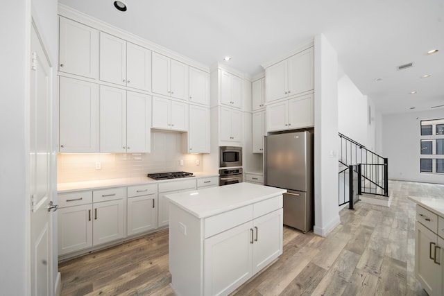 kitchen featuring white cabinetry, stainless steel appliances, light countertops, and a center island