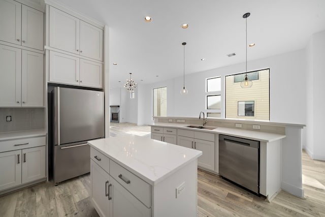 kitchen featuring pendant lighting, stainless steel appliances, a sink, and a center island