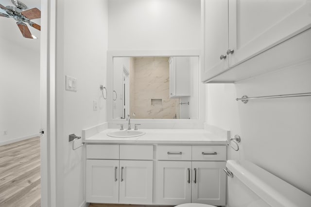 bathroom with baseboards, toilet, ceiling fan, wood finished floors, and vanity