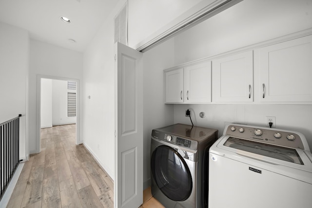 washroom featuring washing machine and dryer, visible vents, baseboards, cabinet space, and light wood finished floors