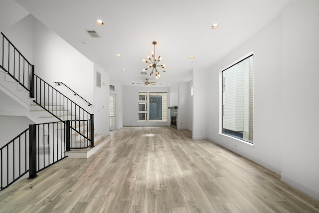 unfurnished living room featuring recessed lighting, visible vents, stairway, light wood-type flooring, and an inviting chandelier