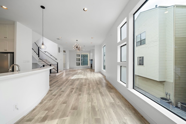 hallway featuring a chandelier, stairway, light wood-style flooring, and recessed lighting