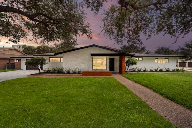 mid-century home with concrete driveway, central AC, a yard, and brick siding