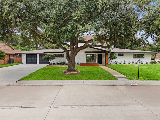 mid-century modern home featuring a garage, concrete driveway, a front lawn, and brick siding