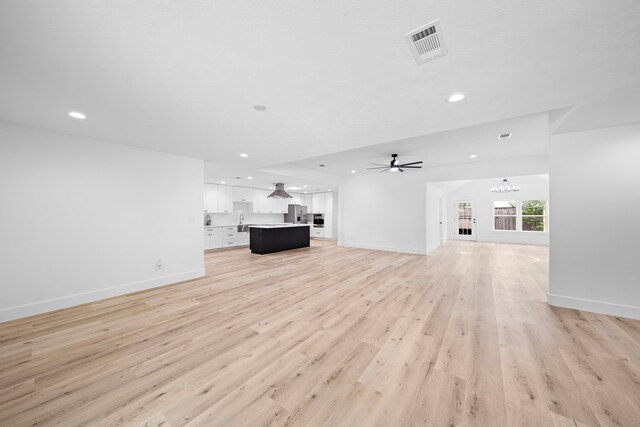 4102 Levonshire Dr, Houston, TX 77025 - unfurnished living room featuring light wood-style floors, recessed lighting, a ceiling fan, baseboards, and a chandelier