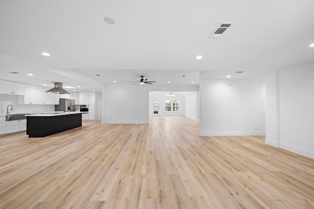 unfurnished living room with recessed lighting, a sink, visible vents, baseboards, and light wood finished floors