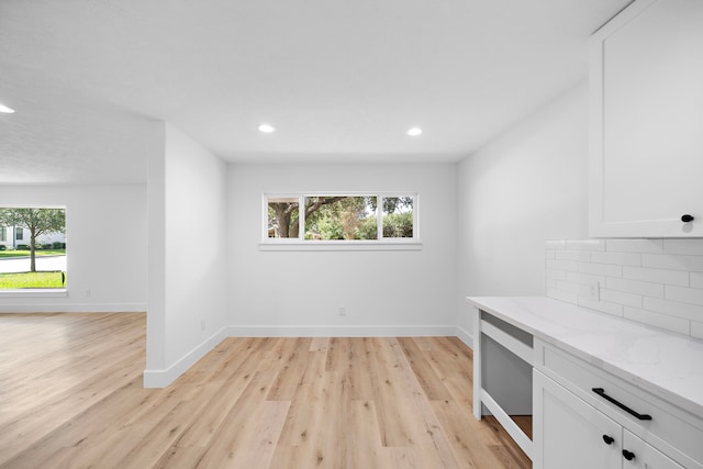 interior space featuring baseboards, a healthy amount of sunlight, and light wood finished floors