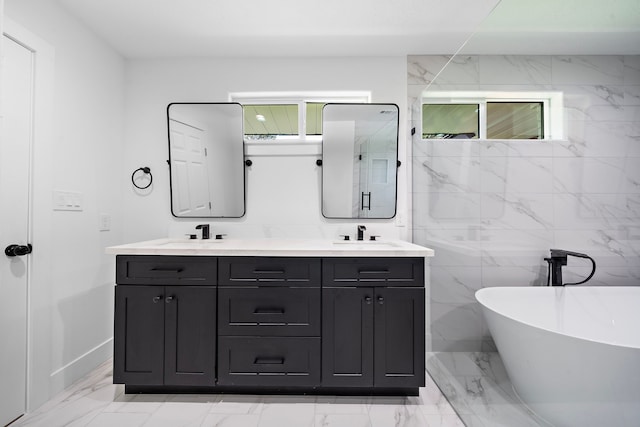 bathroom with a soaking tub, marble finish floor, a sink, and double vanity