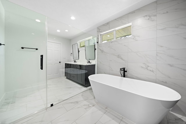 full bath featuring double vanity, baseboards, marble finish floor, a freestanding bath, and recessed lighting