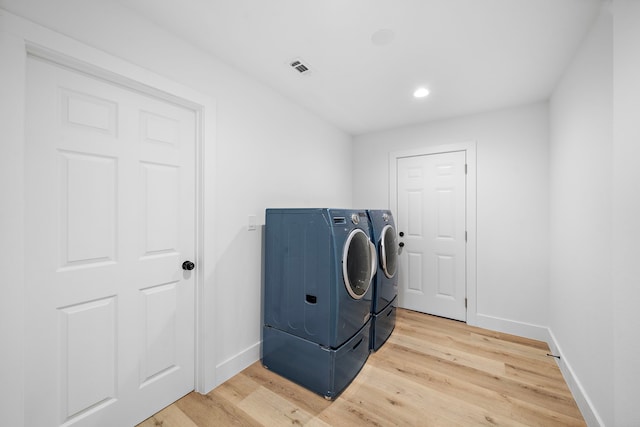 laundry area with light wood-type flooring, laundry area, washing machine and dryer, and baseboards