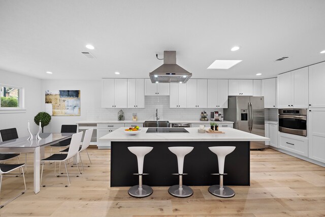 4102 Levonshire Dr, Houston, TX 77025 - kitchen with stainless steel appliances, exhaust hood, a sink, a center island, and a kitchen bar