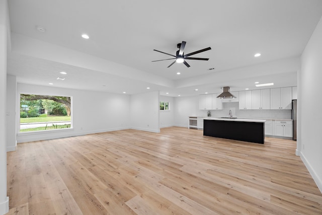 unfurnished living room with baseboards, light wood-type flooring, a wealth of natural light, and recessed lighting