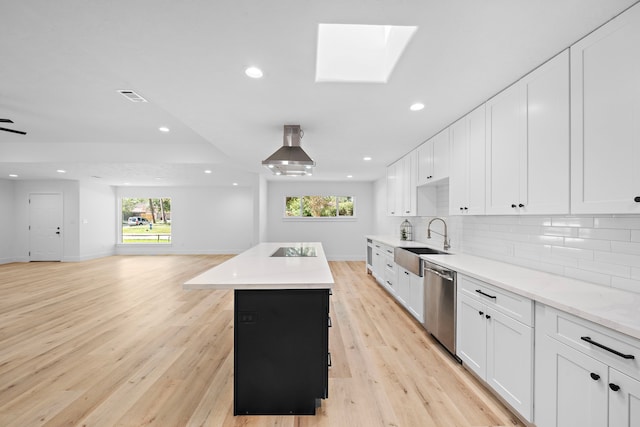 kitchen featuring decorative backsplash, stainless steel dishwasher, open floor plan, a kitchen island, and a sink