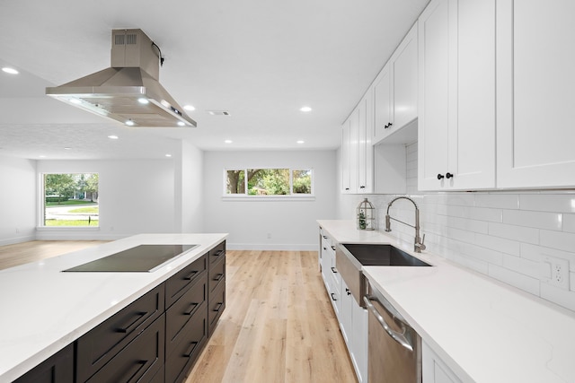 kitchen with white cabinets, island exhaust hood, black electric stovetop, stainless steel dishwasher, and a sink