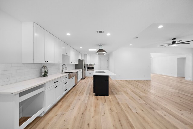 4102 Levonshire Dr, Houston, TX 77025 - kitchen with appliances with stainless steel finishes, recessed lighting, white cabinetry, tasteful backsplash, and light countertops