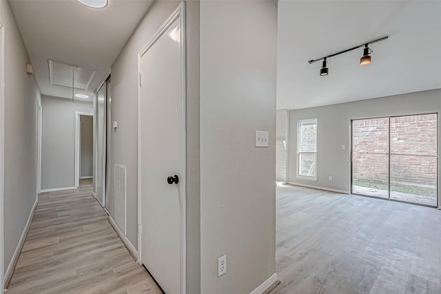 hall featuring rail lighting and light hardwood / wood-style flooring