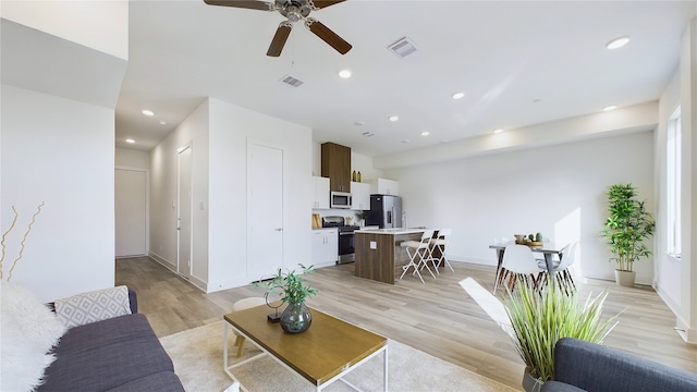 living room featuring baseboards, light wood-type flooring, visible vents, and recessed lighting