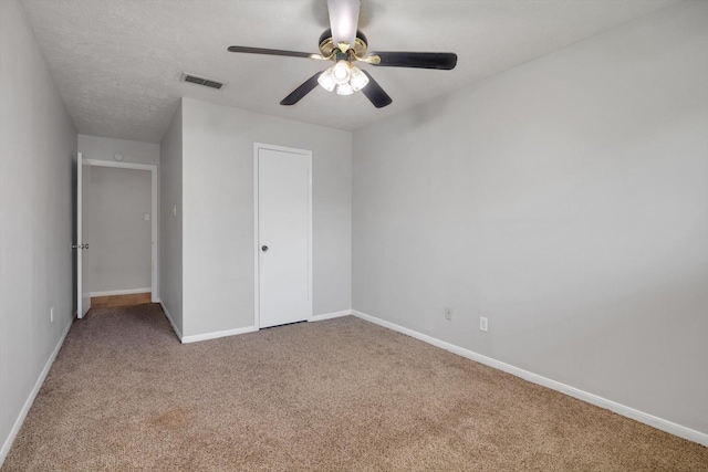 unfurnished bedroom with a ceiling fan, carpet flooring, visible vents, and baseboards