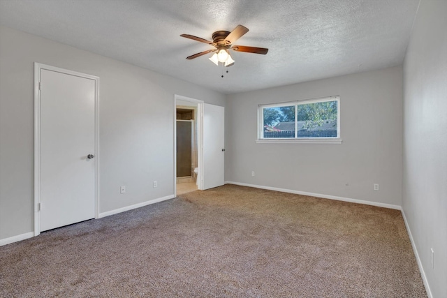 unfurnished bedroom featuring baseboards, connected bathroom, ceiling fan, a textured ceiling, and carpet floors