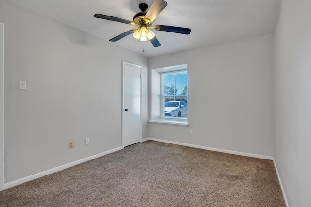 carpeted spare room with ceiling fan and baseboards