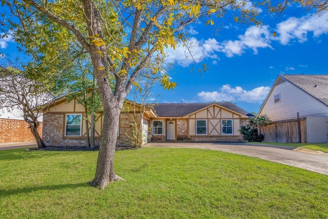 view of front of house with brick siding, an attached garage, a front yard, fence, and driveway