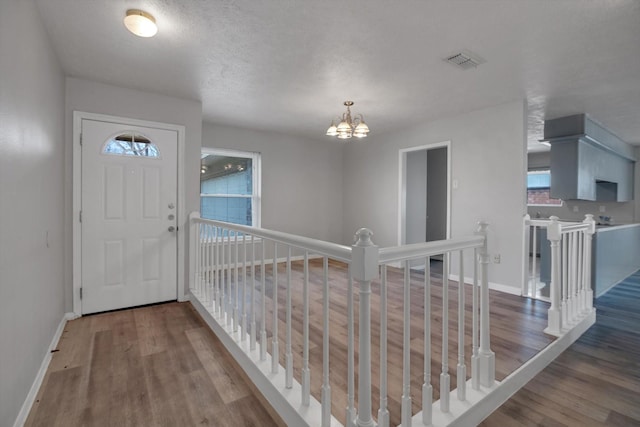 foyer featuring baseboards, visible vents, a chandelier, and wood finished floors