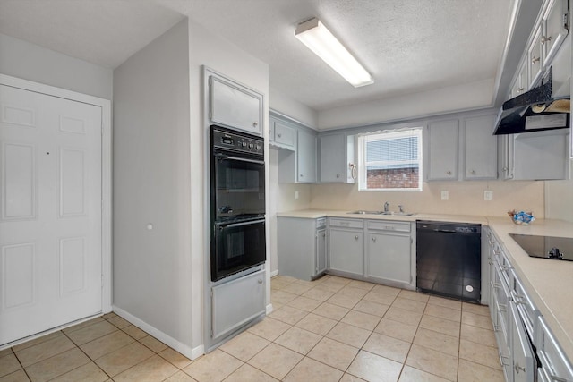 kitchen with light tile patterned floors, light countertops, a sink, a textured ceiling, and black appliances