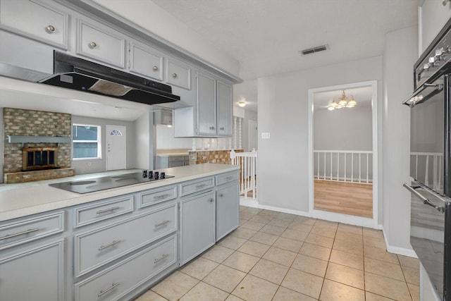 kitchen featuring light countertops, visible vents, gray cabinetry, under cabinet range hood, and black appliances