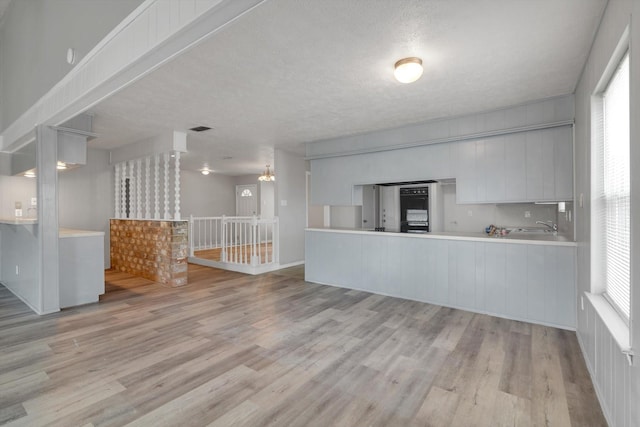 kitchen featuring a textured ceiling, wood finished floors, and a healthy amount of sunlight