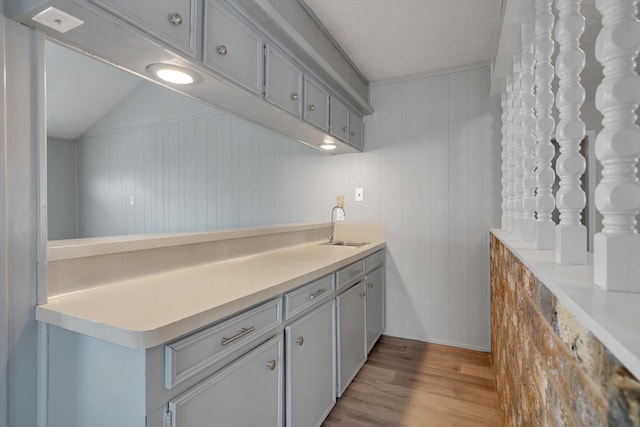 kitchen with gray cabinetry, light countertops, a sink, and light wood-style floors