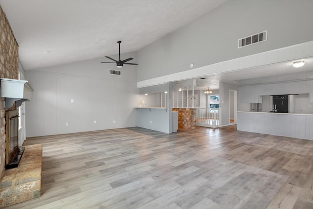 unfurnished living room with ceiling fan, a fireplace, wood finished floors, and visible vents