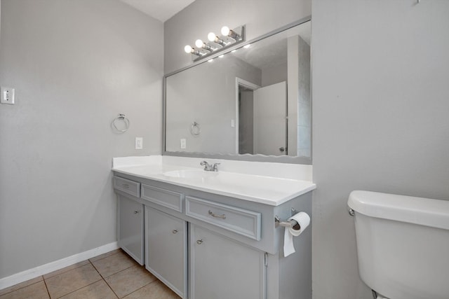 bathroom with toilet, tile patterned flooring, vanity, and baseboards