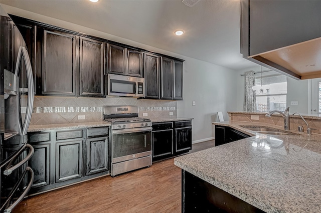 kitchen featuring dark brown cabinetry, light wood-style flooring, a sink, appliances with stainless steel finishes, and decorative backsplash