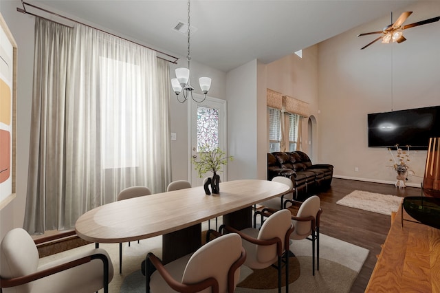 dining room featuring arched walkways, dark wood finished floors, visible vents, vaulted ceiling, and ceiling fan with notable chandelier