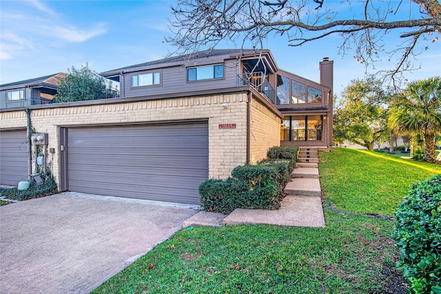 view of front facade with brick siding, a front yard, a balcony, a garage, and driveway