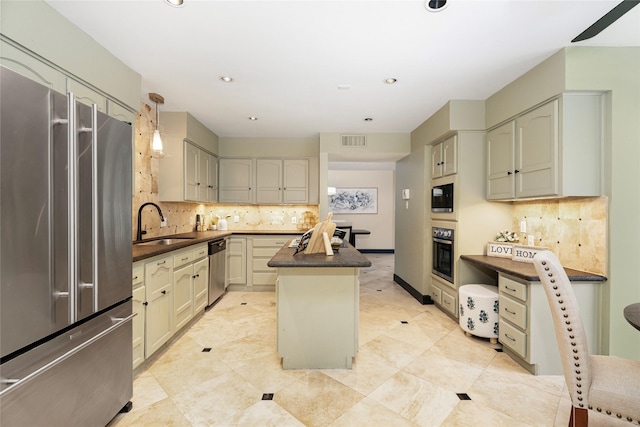 kitchen with cream cabinets, a sink, a kitchen island, appliances with stainless steel finishes, and dark countertops