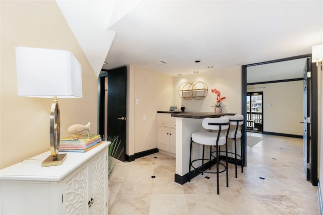 18138 Bal Harbour Dr, Houston, TX 77058 - kitchen with a breakfast bar, white cabinetry, baseboards, dark countertops, and light tile patterned flooring